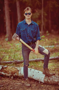 Vahşi ormanda baltası olan yakışıklı, güçlü bir oduncunun tam boy portresi. Doğada çalışmak.