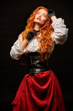 Ortaçağ güzeli, uzun kızıl saçlı, siyah arka planda 16.-17. yüzyıldan kalma tarihi bir kostüm giymiş. Tarihi bir macera romanının kahramanı.. 