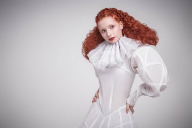 Moda sanat tarihi. Geç rönesans dalgalı yakalı beyaz bir elbise içinde poz veren gür kırmızı kıvırcık saçlı sofistike bir kadın model. Stüdyo portresi. Boşluğu kopyala. 