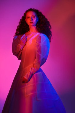 Moda sanatı. Beyaz bir sanat elbisesi içinde poz veren gür kırmızı kıvırcık saçlı sofistike bir kadın modelin portresi. Karmaşık renkli bir stüdyo portresi.