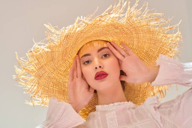 Portrait of a beautiful romantic girl in a straw hat and white blouse. Summer season. Beauty and cosmetics.