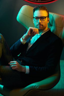  Zarif takım elbiseli, gözlüklü, lüks bir dairede deri koltukta oturan saygıdeğer orta yaşlı bir adamın portresi. Başarı ve zengin yaşam tarzı. İş adamı. Erkek modası.