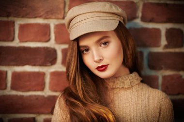 Gülümseyen, doğal makyajlı ve açık bej bluzlu güzel bir kızın yakın plan portresi. Tuğla duvar arka planı. Güzellik, kozmetik konsepti.  