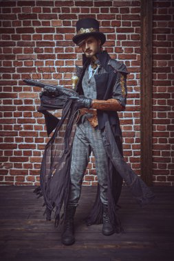 Cesur bir erkek savaşçının duvar arkasında bir silahla poz verdiğinin tam boy portresi. Steampunk dünyası. 