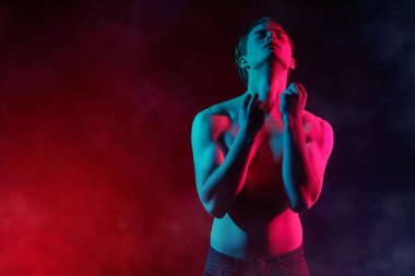 Kırmızı ve mavi ışıkta çıplak bedenle poz veren yakışıklı bir genç adamın portresi. İnsanın güzelliği ve sağlığı. Resim..