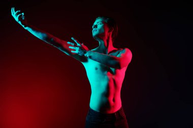 Kırmızı ve mavi ışıkta çıplak bedenle poz veren yakışıklı bir genç adamın sanat portresi. İnsanın güzelliği ve sağlığı. Resim..