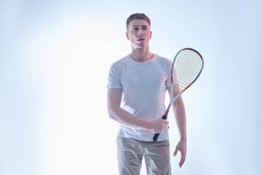 Şaşkın sporcunun duvar tenisi raketiyle portresi. Aktif yaşam tarzı. Spor ve sağlık hizmetleri. Beyaz arkaplanda stüdyo resmi