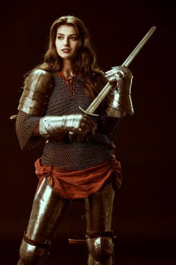 A brave noble warrior woman in chainmail and plate armor poses holding her sword. Medieval knight. Studio portrait on a black background.  clipart