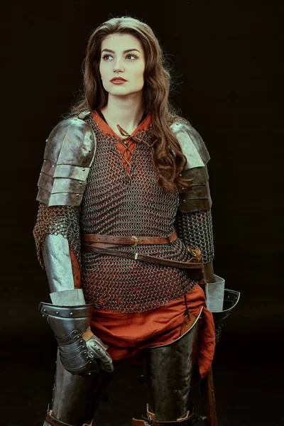 Portrait of a pensive female knight in armor of noble birth standing on a black background. History of the Middle Ages.