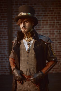 Palto giymiş şık bir steampunk asilzade portresi ve tuğla duvar arkasında silindir şapka. Steampunk dünyası. 