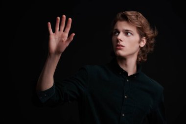 Siyah arka planda dalgalı sarı saçlı yakışıklı bir gencin portresi. Erkek güzelliği. Boşluğu kopyala.