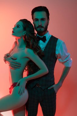 Zarif takım elbiseli yakışıklı pasif adam seksi çıplak kıza sarılıyor. Aşk ve moda.