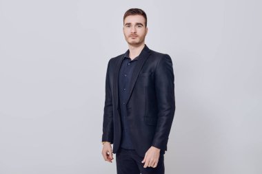 Beyaz bir duvara karşı koyu mavi takım elbiseli yakışıklı bir adamın portresi. İş adamı portresi. Boşluğu kopyala.