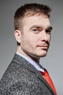 Zarif takım elbiseli modern stil sahibi bir adam gri bir arka planda yan görünüm sergiliyor. Erkek modası.