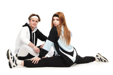 Bir çift modern genç kız ve bir erkek stüdyoda şık spor kıyafetleriyle poz veriyorlar. Spor stili. 