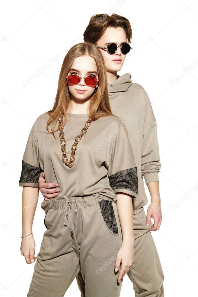 Two modern teenagers a boy and a girl pose together in fashionable sportswear at studio. Sport style. White background.
