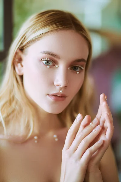 Beauty and jewelry. Close-up portrait of a beautiful blonde girl with fresh shining makeup with pearls. Spa, skincare and cosmetics.