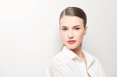 Açık tişörtlü zarif genç bayan stüdyoda açık gri duvarın yanında poz veriyor. Yaz modası. Boşluğu kopyala.