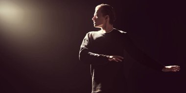 Karanlıkta stüdyoda gözleri kapalı poz veren cesur ve etkileyici genç adamın portresi. Erkek güzelliği. Siyah arkaplan. 