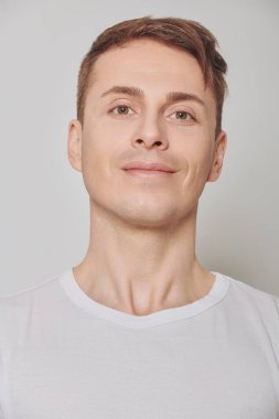 Beyaz arka planda gülümseyen yakışıklı bir adamın yakın portresi. Erkek sağlığı ve güzelliği.