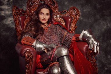 Portrait of a beautiful medieval young woman in knightly armor sitting on a throne. The Middle Ages history.  clipart