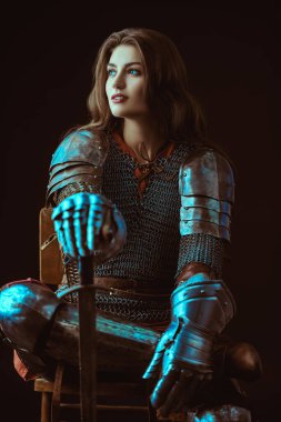 A beautiful noble warrior woman in chain mail and plate armor sits, leaning on her sword. Medieval knight. clipart