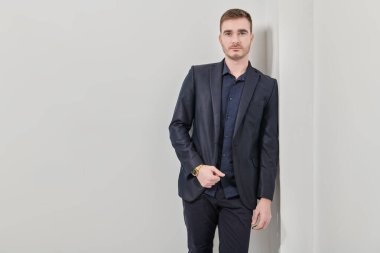 Beyaz bir duvara karşı koyu mavi takım elbiseli yakışıklı bir adamın portresi. İş adamı portresi. Boşluğu kopyala.