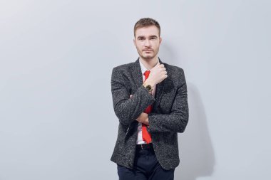 Yakışıklı adam gri takım elbise ve açık gri arka planda kırmızı kravat ile poz veriyor. İş adamı portresi. 