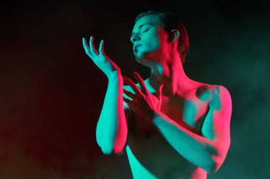 Kırmızı ve yeşil ışıkta çıplak bedeniyle poz veren yakışıklı bir genç adamın sanat portresi. İnsanın güzelliği ve sağlığı. Resim..