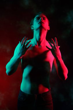 Kırmızı ve yeşil ışıkta çıplak bedeniyle poz veren yakışıklı bir genç adamın sanat portresi. İnsanın güzelliği ve sağlığı. Resim..