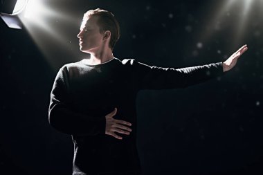 Karanlık ışıkta stüdyoda poz veren cesur ve etkileyici genç adamın portresi. Erkek güzelliği. Siyah arkaplan. 