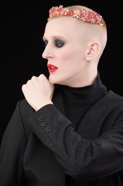 Avangard modası. Kısa saçlı, kadın makyajlı ve siyah arka planda mavi ışık altında poz veren bir mankenin portresi..