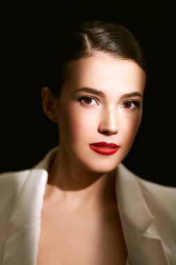 Çekici, esmer bir kadının yakın plan portresi siyah arka planda zarif siyah dantel bir bluzla poz veriyor. Işık ve gölgeli stüdyo portresi. Makyaj ve kozmetik. 