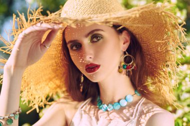 Parktaki ağaç dalları arasında romantik esmer bir kızın portresi. Makyaj ve kozmetik.