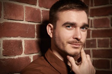 Duvarın arkasında oturan yakışıklı, olgun bir adamın portresini yakından çek. Erkek güzelliği, moda.