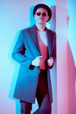 Zarif ceketli, beyaz bir duvarın yanında duran ve gülümseyen orta yaşlı yakışıklı bir adamın portresi. Erkek güzelliği, moda. Yaşam tarzı. Hippi adam.. 