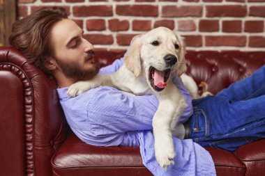 Bir adam ve bir evcil hayvan. Mutlu genç adam evcil köpeği Golden Retriever ile kanepede yatıyor..