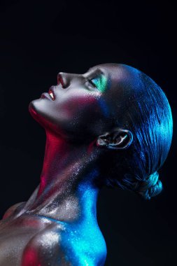 Vücut sanatı projesi. Güzel bir manken kadın portresi. Gözleri kapalı. Siyah arka planda ışıl ışıl parlayan bir makyajı var. Makyaj ve kozmetik.  
