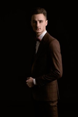Siyah arka planda zarif bir takım elbise ve papyon giymiş yakışıklı bir adamın portresi. İş stili. Erkek modası.