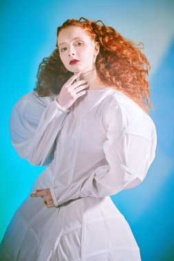 Açık renkli bir elbise içinde poz veren kıvırcık saçlı fantastik bir kadın model. Bir stüdyo portresi. Moda sanatı. 