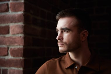 Duvarın arka planında pencereden bakan yakışıklı, olgun bir adam. Erkek güzelliği, moda. Kişinin portresini yakından çek..