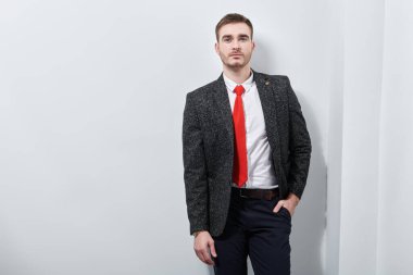 Yakışıklı adam gri takım elbise ve açık gri arka planda kırmızı kravat ile poz veriyor. İş adamı portresi. 