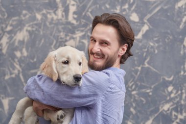 Arka planda Golden Retriever köpeğine sarılan mutlu bir gencin portresi. Bir adam ve bir evcil hayvan. 