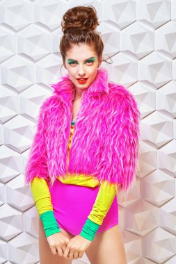 Beyaz arka planda parlak renkli giysiler içinde fevkalade modaya uygun bir model. Aktif parlak yaşam tarzı.