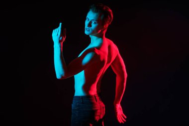 Kırmızı ve mavi ışıkta çıplak bedenle poz veren yakışıklı bir genç adamın sanat portresi. İnsanın güzelliği ve sağlığı. Resim..