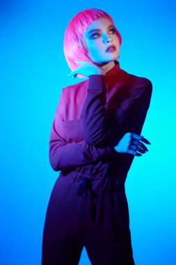 Parlak makyajlı ve gölgelerde poz veren pembe saçlı muhteşem bir genç kadın portresi. Makyaj malzemeleri ve saç stili. Moda güzelliği trendleri.  