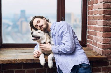 Bir adam ve Golden Retriever 'ı pencerenin önünde poz veriyorlar. Hayvanlar için dostluk ve sevgi.