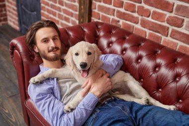 Bir adam ve bir evcil hayvan. Mutlu genç adam evcil köpeği Golden Retriever ile kanepede yatıyor..