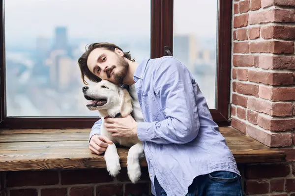 Bir adam ve Golden Retriever 'ı pencerenin önünde poz veriyorlar. Hayvanlar için dostluk ve sevgi.