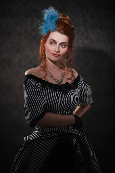 Portrait of a beautiful red-haired woman in a 19th century dress on a vintage background. Fashion history, makeup and hairstyle.